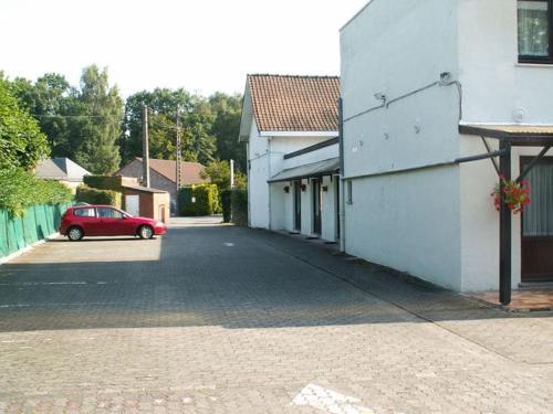 a red car parked in a parking lot next to a building at Résidence Rachel 23 in Mons