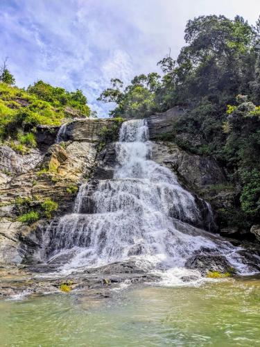 a waterfall on the side of a mountain with a body of water at Diyaluma NAS Villa in Koslanda