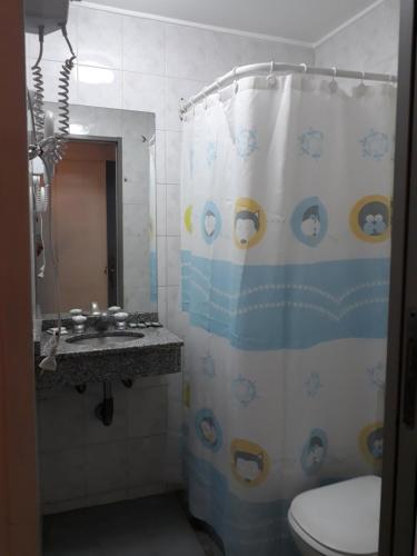 a bathroom with a shower curtain with a toilet and a sink at Hotel Plaza Roma in Buenos Aires