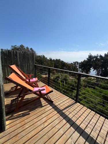 a wooden deck with two chairs sitting on top of it at Lofts - Casa El Pangue, Zapallar in Zapallar
