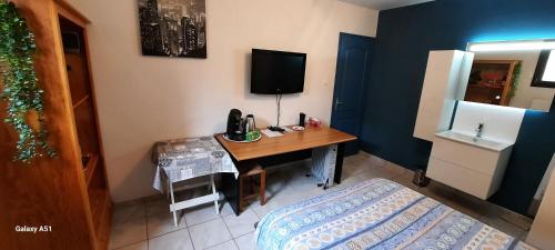 Cette chambre comprend un bureau, une télévision et un lit. dans l'établissement chez Jocelyne, à Jassans-Riottier