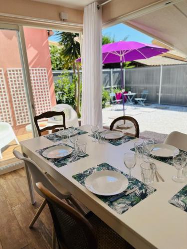une table avec des assiettes et des verres sur une table avec un parasol dans l'établissement Bastide Saint Vincent, au Grau-dʼAgde