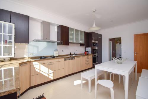 a kitchen with wooden cabinets and a white table at Spacious 4-Bedroom Villa with Private Heated Pool in Quinta da Beloura Sintra Ideal for Families & Long Stays in Sintra