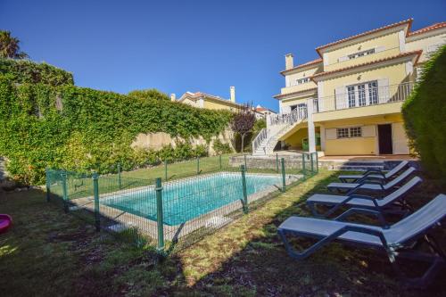 a swimming pool with lounge chairs next to a house at Spacious 4-Bedroom Villa with Private Heated Pool in Quinta da Beloura Sintra Ideal for Families & Long Stays in Sintra