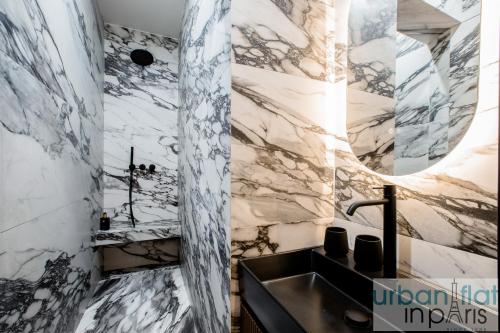 La salle de bains est pourvue d'un lavabo et d'un mur en marbre. dans l'établissement Urban Flat 197 - Appartement Saint Honore Champs Elysees, à Paris