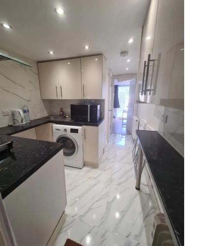 a white kitchen with a washer and dryer in it at 2 bed flat in Heathrow London Free parking in Feltham