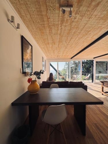 a dining room with a table and a woman sitting in a room at Lofts - Casa El Pangue, Zapallar in Zapallar