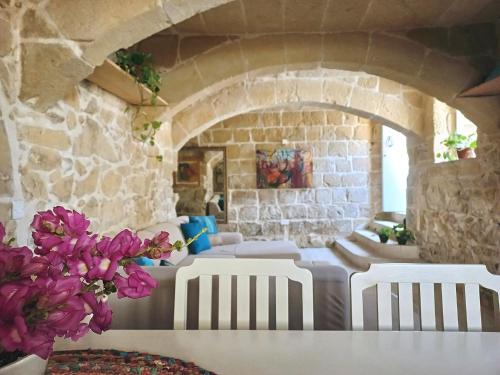 a room with white chairs and a stone wall at Virginia Farmhouse in Kerċem