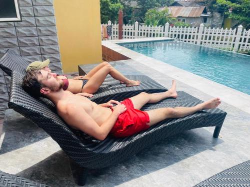a man laying on a wicker chair next to a swimming pool at Canal's Edge in Negombo