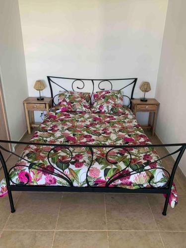 - un lit avec une couette à fleurs et 2 tables dans l'établissement La Grande-Motte sea view apartment, à La Grande Motte