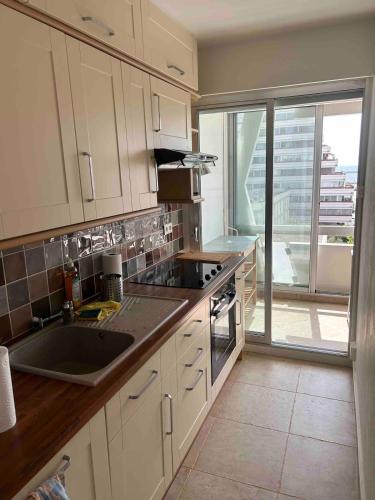 une cuisine avec des placards blancs et une grande fenêtre dans l'établissement La Grande-Motte sea view apartment, à La Grande Motte