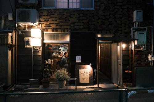 a man standing inside of a restaurant at night at Hotel Suzumeya Tsukiji plus kitchen in Tokyo