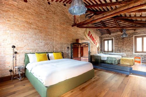 ヴェネツィアにあるGolden Luxe - Glass of Murano luxury apartmentのレンガの壁に大きなベッドが備わるベッドルーム1室が備わります。