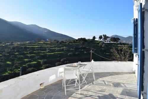 a table and chairs on a patio with a view of a hill at Arch House Sifnos in Apollonia