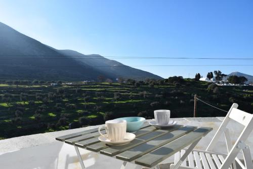 a table with two cups and two chairs on top of a mountain at Arch House Sifnos in Apollonia