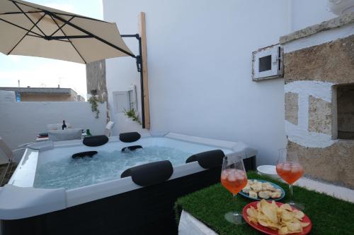a hot tub on a patio with glasses of wine at Casina Li Fumareddhi in Corsano