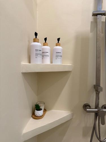three bottles of toiletries sit on shelves in a bathroom at High-In Holiday Home&Villa in Ko Phangan