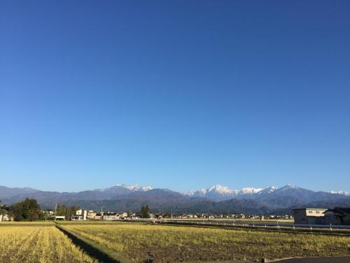 a field of grass with mountains in the background at Tsurugi Koizuki in Kamiichi