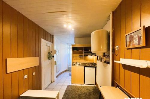 - une petite cuisine avec des murs en bois et une cuisinière dans l'établissement Studio rdc mont dore centre, à Le Mont-Dore