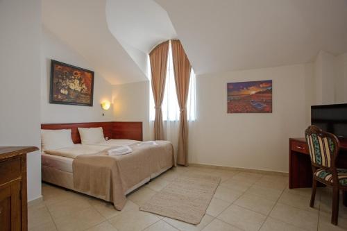 a bedroom with a bed and a television in it at Hotel CENTRAL Balchik in Balchik
