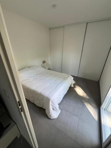 un lit blanc dans une chambre avec une fenêtre dans l'établissement Magnifique T2 au Cœur de Montpellier, à Montpellier