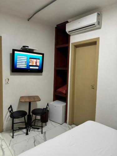 a bedroom with a television and a table and chairs at New Point Hotel in Sao Paulo