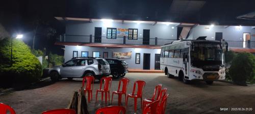 un autobus parcheggiato davanti a un edificio con sedie rosse di Mountain View guest house a Madikeri