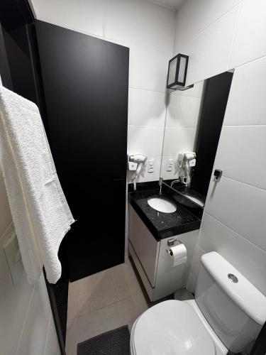 a bathroom with a white toilet and a sink at Prédio San Paolo - Bairro Santa Mônica próximo a UFU / Prefeitura / Center Shopping in Uberlândia