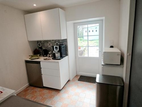  La cuisine est équipée de placards blancs et d'un réfrigérateur. dans l'établissement Maison T2 Meublé à la campagne, à Saint-Maurice-le-Girard