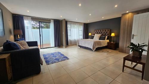 a bedroom with a bed and a couch in a room at Belle Vie Boutique Guesthouse in Pretoria