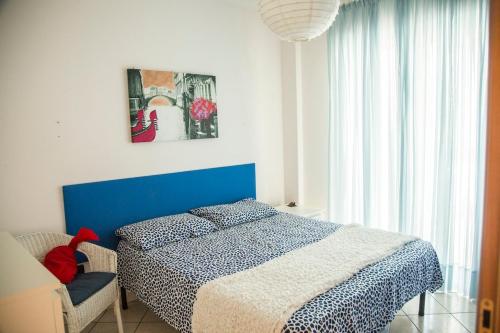 a bedroom with a blue and white bed and a chair at House 30 meters from the sea with gated parking in Marina di Montenero