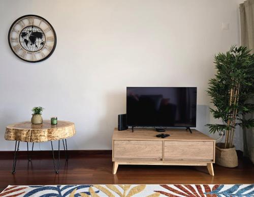 a living room with a flat screen tv on a wooden cabinet at Green Seaty View in Ponta Delgada