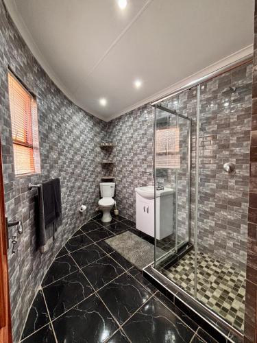 a bathroom with a glass shower and a toilet at Pazuri Homestay in Kempton Park