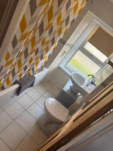 a bathroom with a toilet and a sink and a window at Cosy Seaside Cottage in Allonby