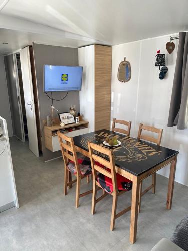une table de salle à manger et des chaises dans une pièce dans l'établissement mobilhomme 3 Chambres avec piscine, à Camiers