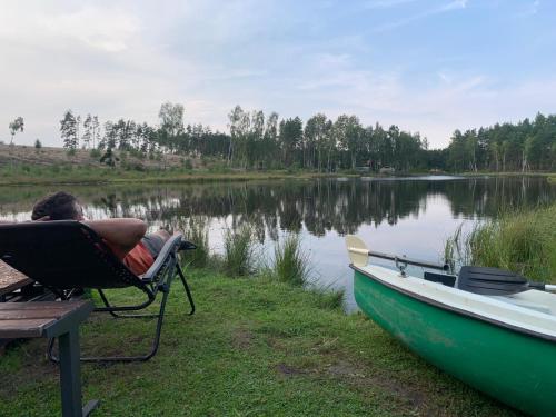a man sitting in a chair next to a boat at Ekolandia in Tuszkowy