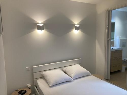 - un lit avec deux oreillers et deux lumières sur le mur dans l'établissement Appartement Le Cœur Grau, au Grau-du-Roi
