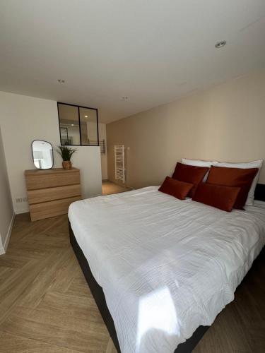 une chambre avec un grand lit blanc avec des oreillers rouges dans l'établissement L'Escapade Amboisienne, à Amboise