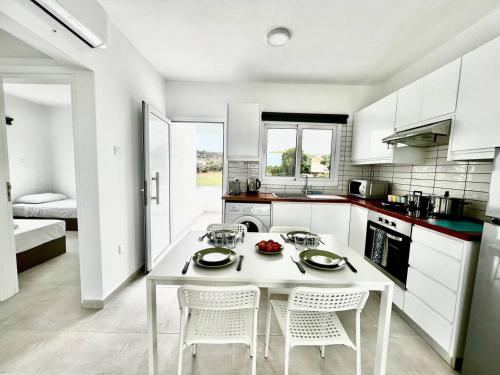 a white kitchen with a white table and chairs at Protaras Cozy2bedroom Apartment in Paralimni