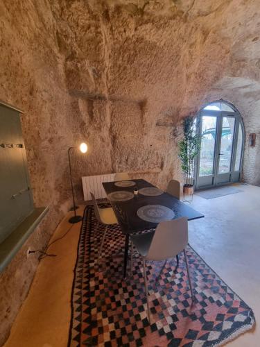 d'une salle à manger avec une table et des chaises dans un mur en pierre. dans l'établissement Troglo en bord de Loire, entre vignes et châteaux, à Montlouis-sur-Loire