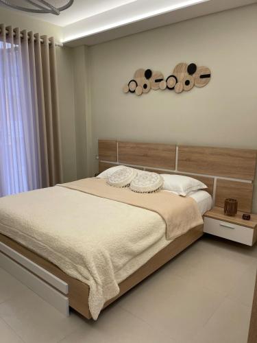 una camera da letto con un grande letto con testiera in legno di Sunset Rental a Durrës