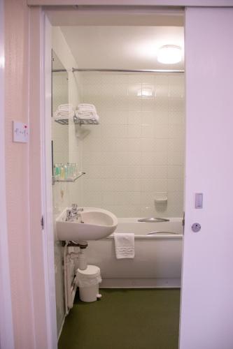 a bathroom with a sink and a tub and a toilet at Alma Lodge Hotel in Stockport