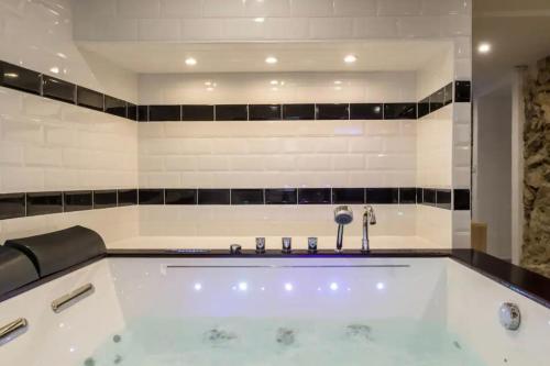 a large bath tub in a bathroom with black and white tiles at La Suite Confidentielle - Balneo - Sauna - Hypercentre in Cannes
