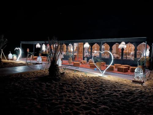a building with lights in front of it at night at Merzouga Queen Luxury Camp in Merzouga