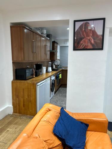 a living room with a couch and a kitchen at A Cosy Ground Floor Flat in London