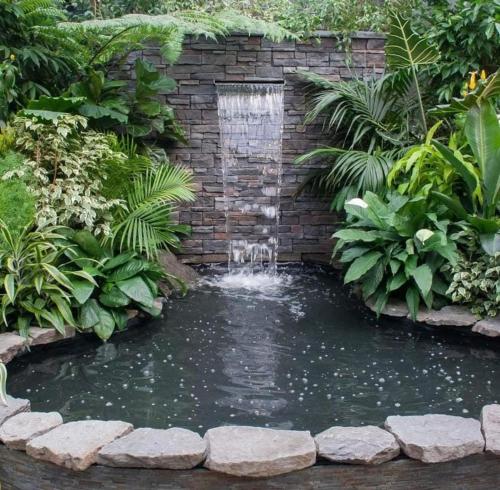 a pond with a waterfall in a garden at Villa relax todo verde natural in Almuñécar