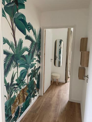 un couloir orné d'une fresque murale de palmiers dans l'établissement Jolie maison proche des plages, à Plonéour-Lanvern