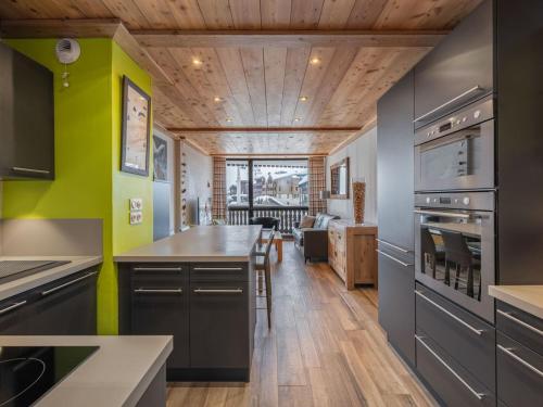 Il comprend une cuisine dotée de plafonds en bois et de murs verts. dans l'établissement Skis aux pieds - 9 personnes - Val Thorens, à Val Thorens