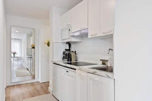 une cuisine blanche avec des armoires blanches et un évier dans l'établissement VILLA RENAISSANCE II - Somptueux deux pièces - Monaco - Parking Gratuit, à Beausoleil