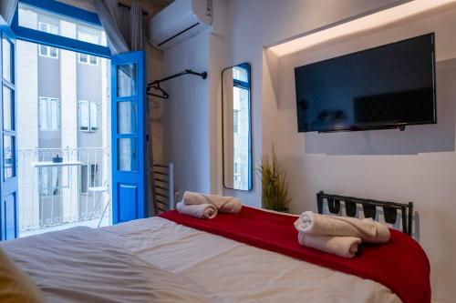 a bedroom with a bed and a flat screen tv at Mandera's Boutique Suites & Dorms in Valletta